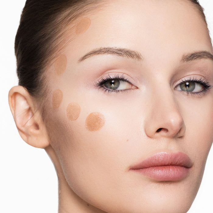Close-up of a woman's face with cream bronzer applied to her cheek.
