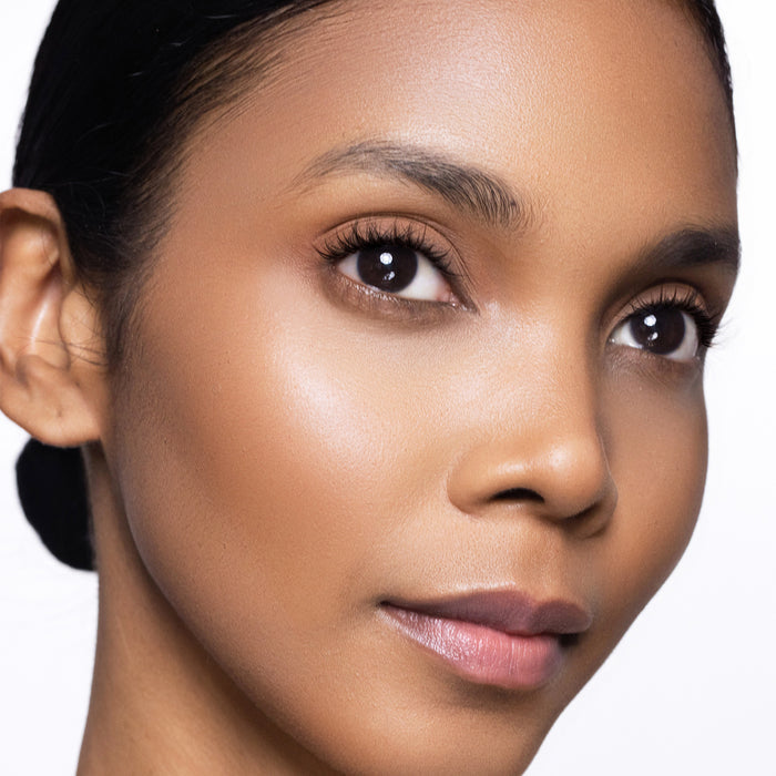 Close-up of a models face with a neutral background focusing on cream bronzer