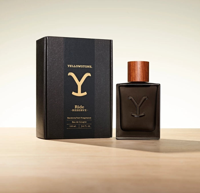 A bottle of Tru Fragrance Yellowstone Ride Reserve Men's Cologne next to its black packaging box with the 'Yellowstone' logo in gold.