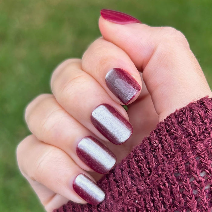 Hand wearing Velvet Berry - Press-On | Extra Short | Squoval false nails in shimmery berry finish with knitted sweater background