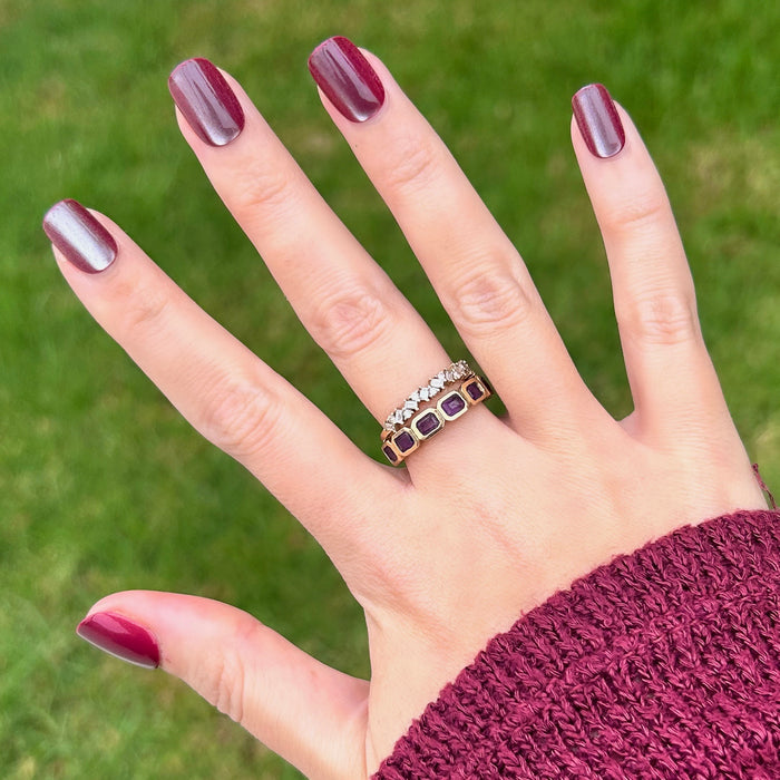 Hand showing Velvet Berry - Press-On | Extra Short | Squoval with shimmery chocolate brown finish outdoors on green grass background