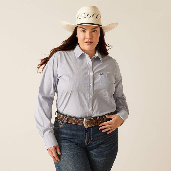 Women's Ariat long sleeve wrinkle resistant stretch shirt in True Blue. This Western style shirt is a blue and white pinstripe. Front view showing shirt tucked in and Ariat shield logo stitched on left chest pocket.