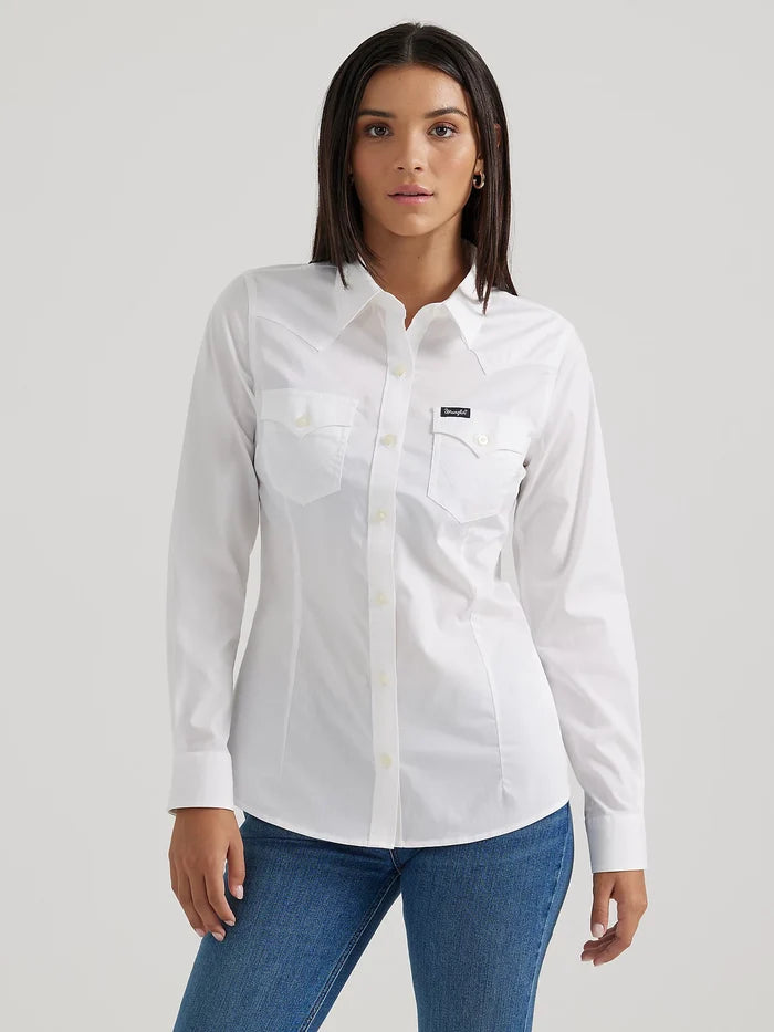 Full view of a woman wearing a long sleeve white Wrangler shirt with a spread collar, front yokes, button flap front pocket and button down front pockets.