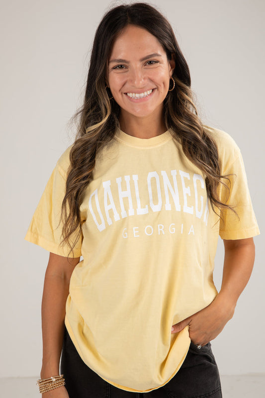 Woman wearing a yellow t-shirt with 'GAHLOWNE' text, standing against a plain background