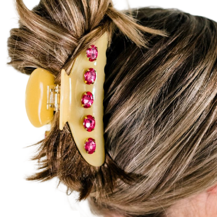 Hair clip with pink gemstones in a person's hair on a white background